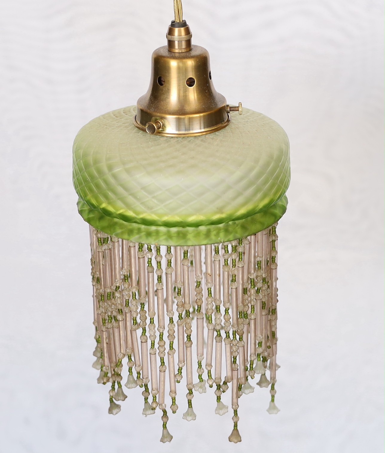 A 1920s French quilted glass light fitting with beaded fringe, height 30cm. width 15cm